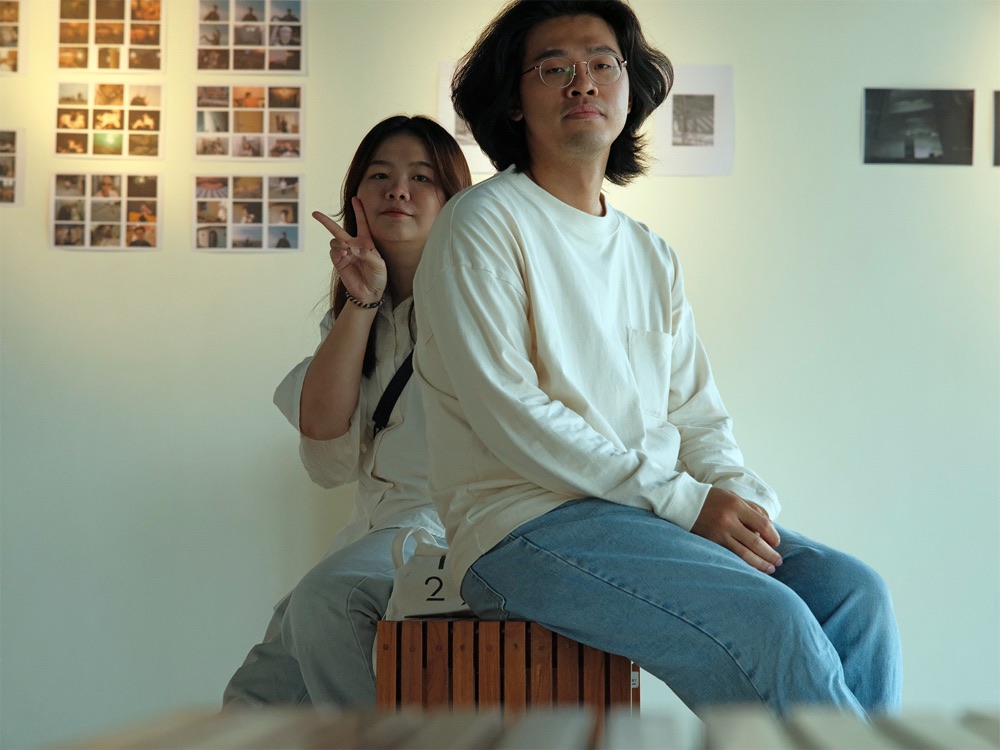 許鎮富與劉乃綺在展場裡，坐在木箱上